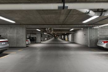 A long, narrow parking garage with cars parked on both sides.